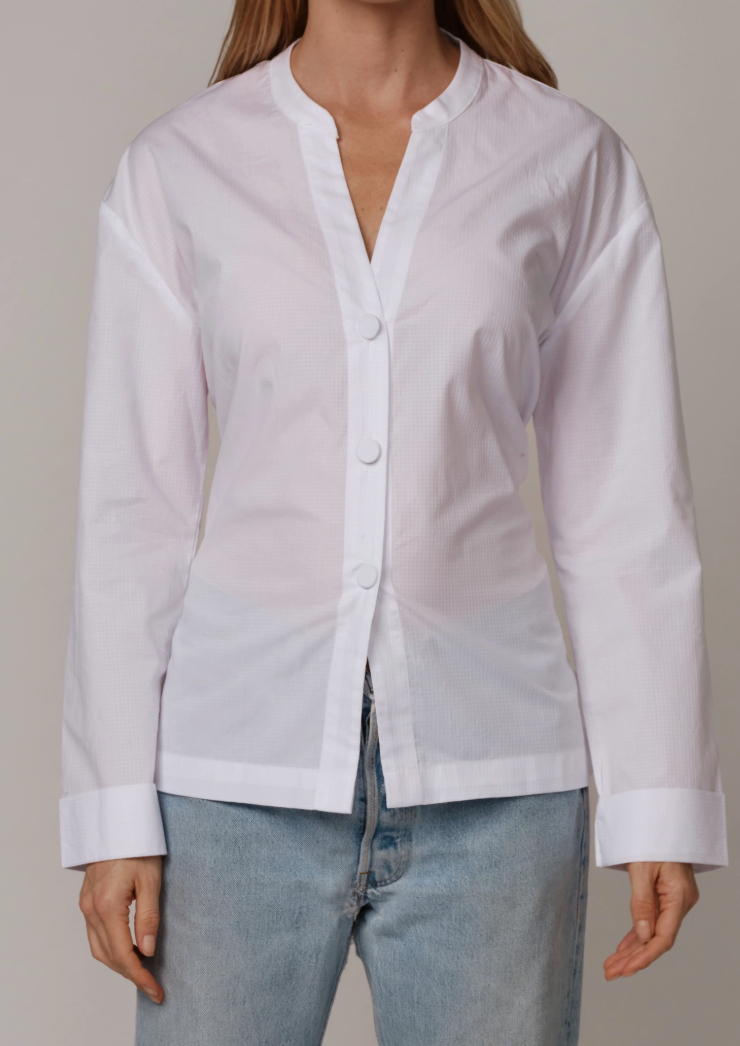 White long-sleeve button-up shirt with mandarin collar and relaxed fit, styled with light blue jeans.