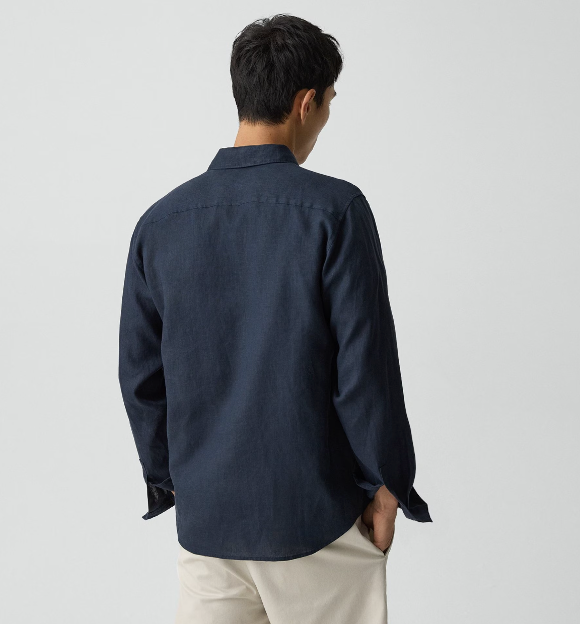 Back view of man wearing Theory Irving LS Relaxed Shirt in navy blue with white pants.