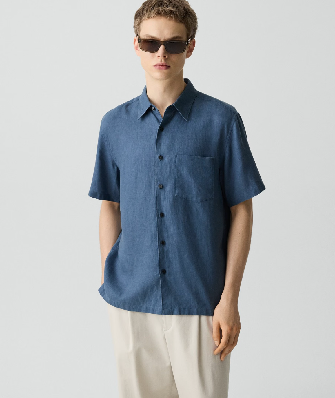 Theory Irving short-sleeve button-up shirt in blue worn by model with sunglasses and light pants