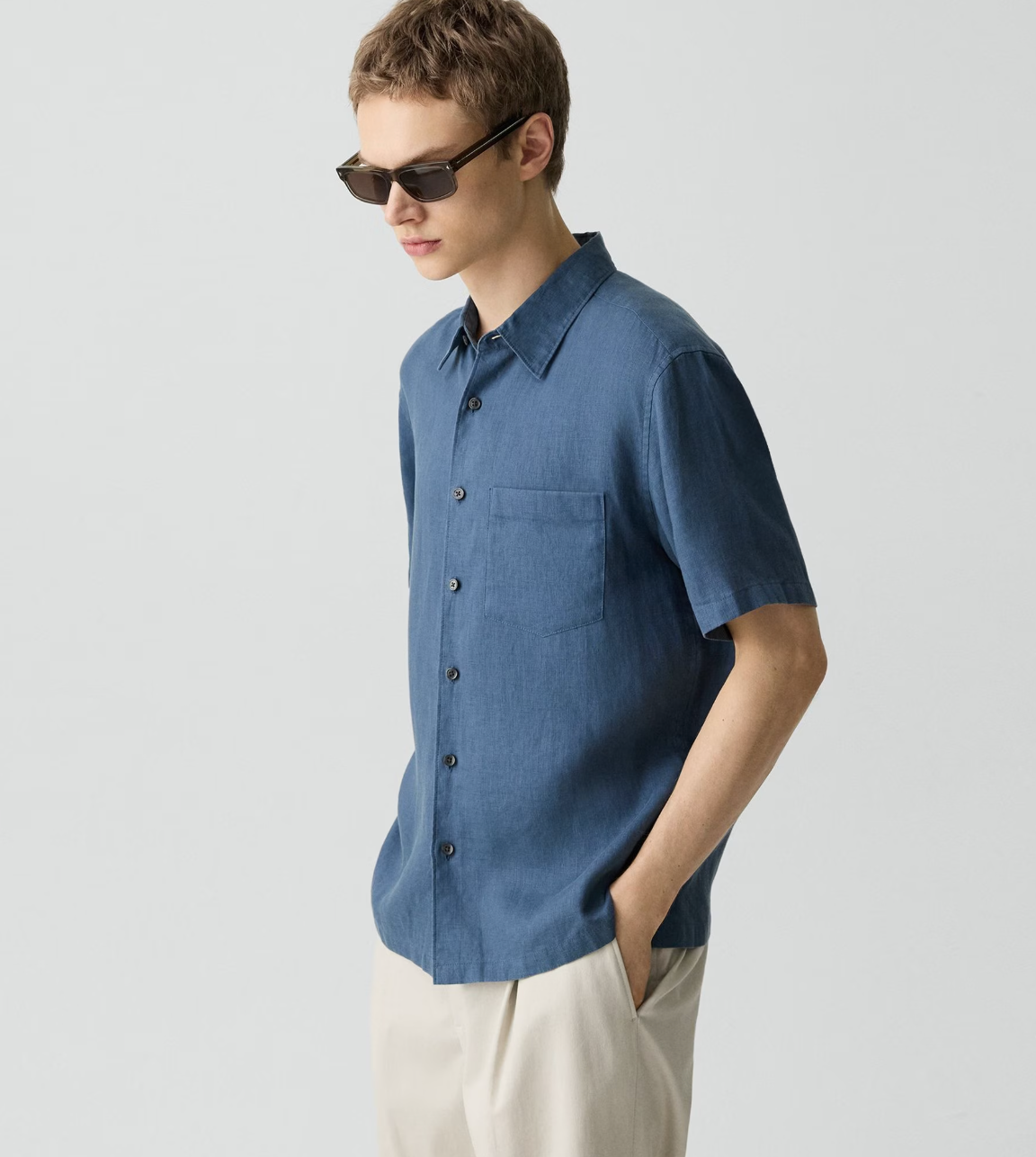 Theory Irving short-sleeve button-up shirt in blue worn by model with sunglasses and light colored pants.