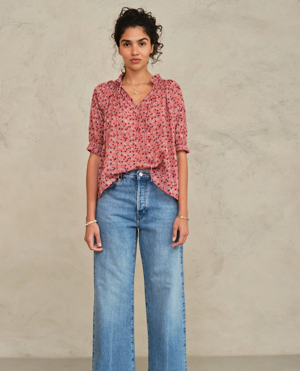Woman wearing MABE Darla Print long sleeve top in rose floral pattern with wide-leg blue jeans.