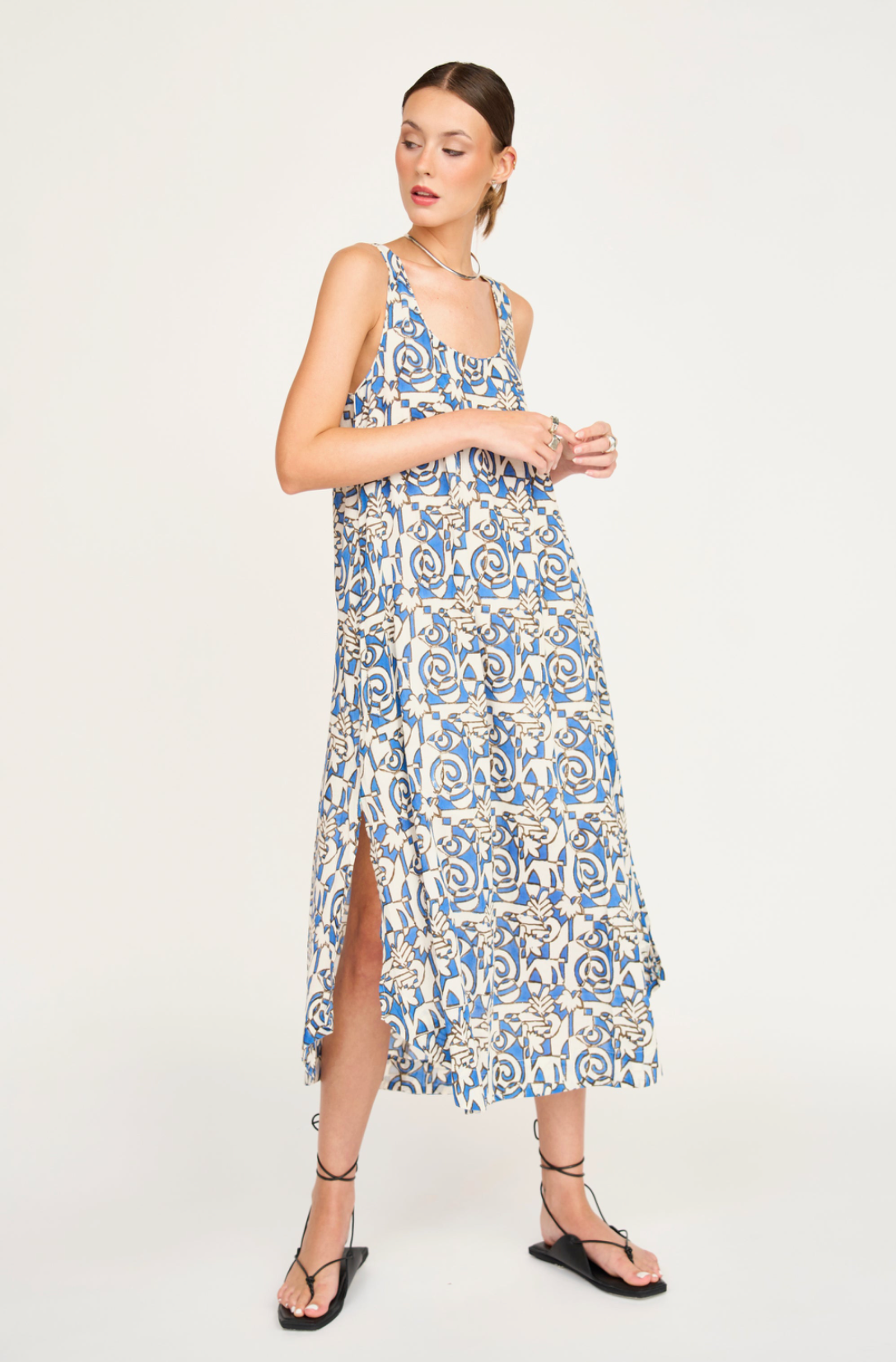 Woman wearing blue and white patterned midi dress with side slit and strappy sandals