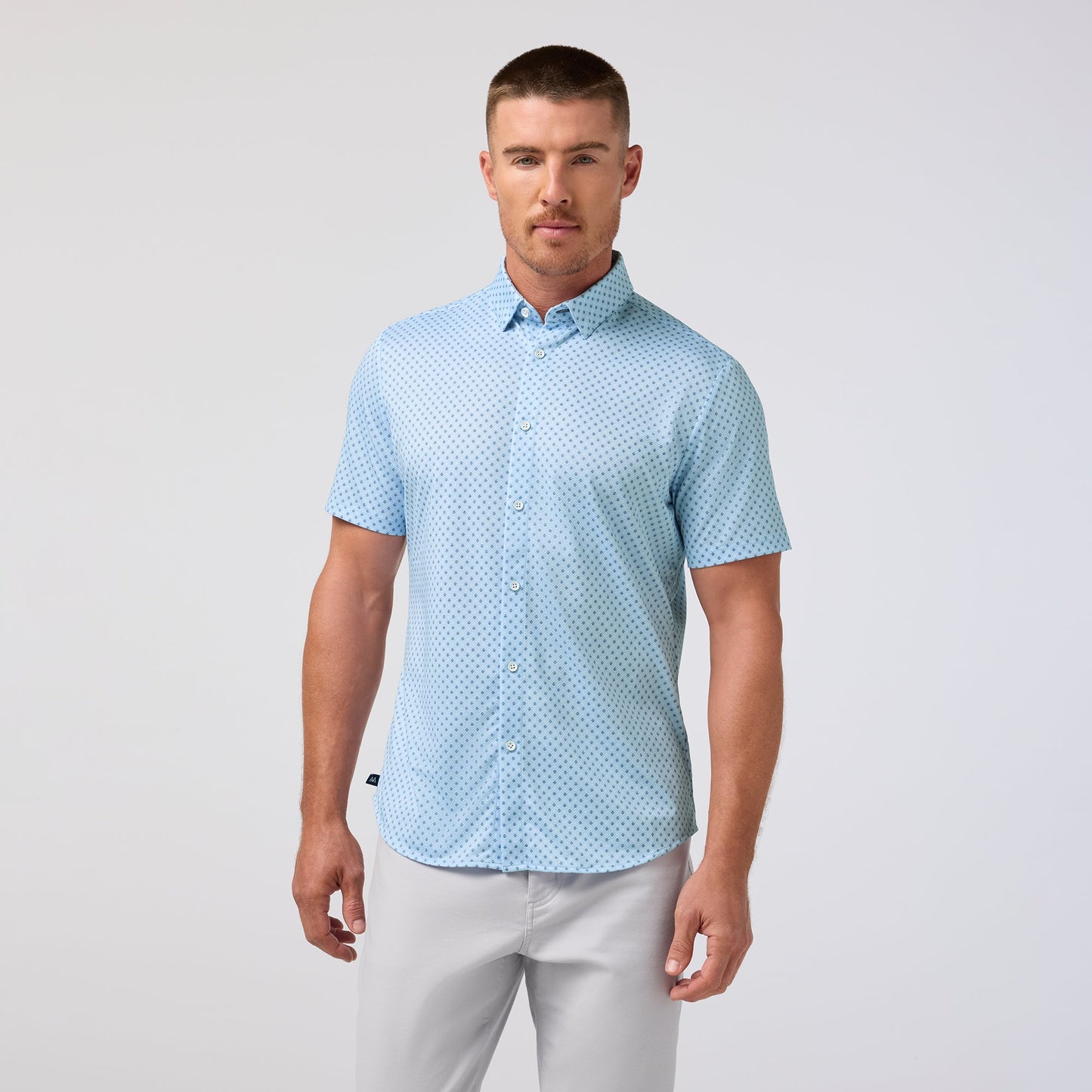 Man wearing light blue short sleeve shirt with small circle pattern and white pants
