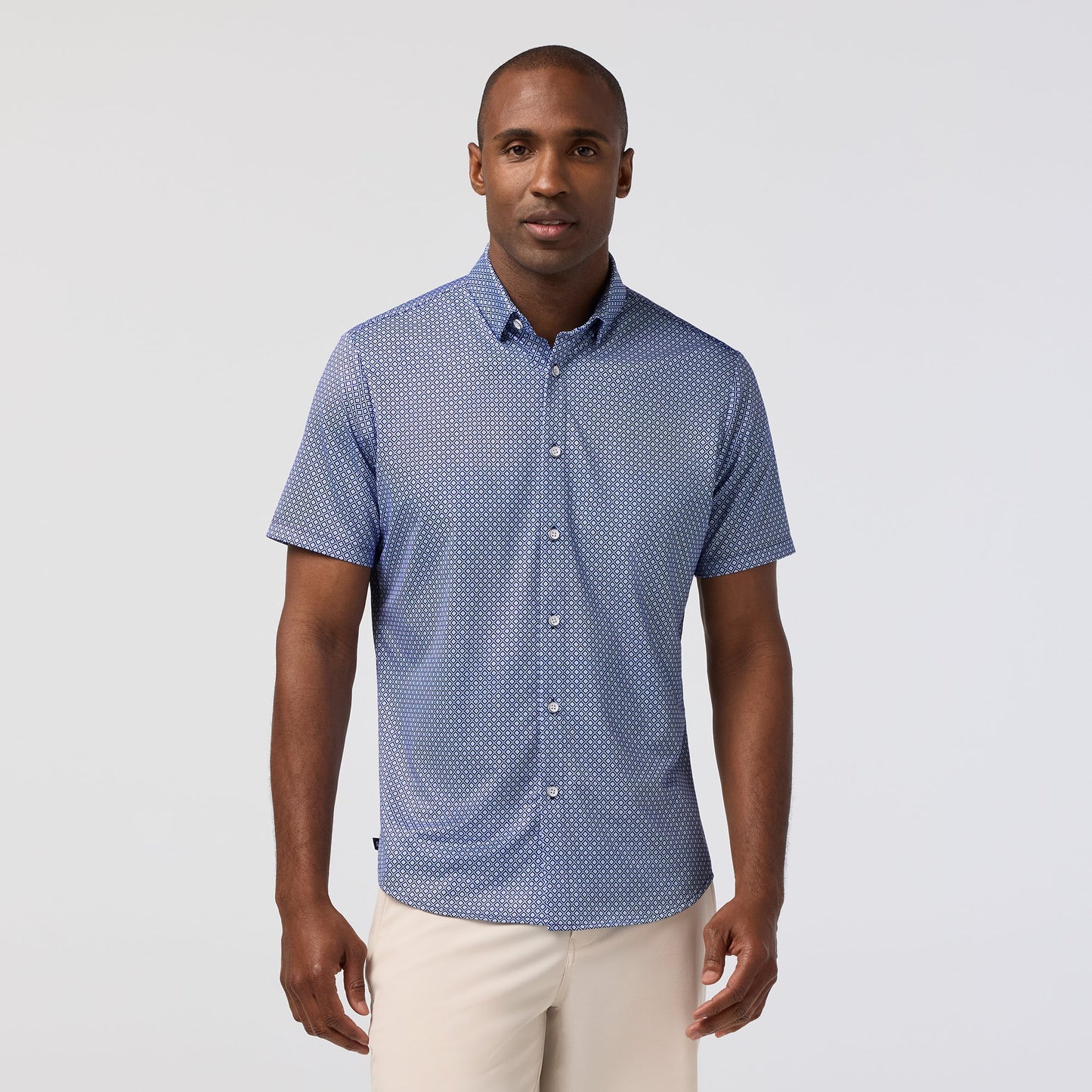 Man wearing navy blue short sleeve button-down shirt with white geometric diamond pattern