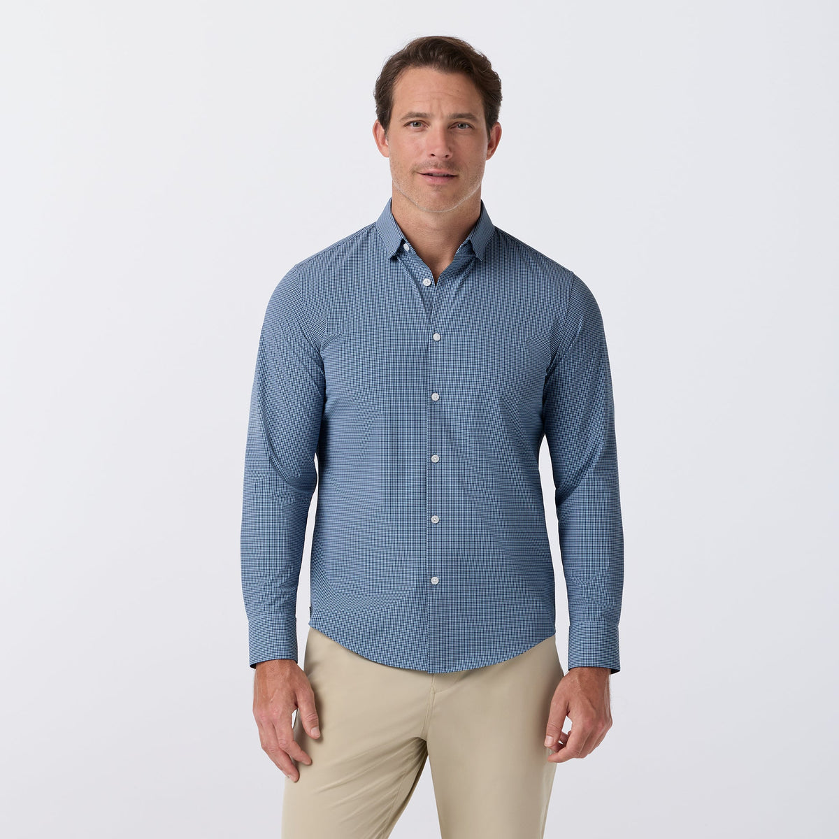 Man wearing Mizzen+Main Leeward No Tuck long sleeve dress shirt in midnight navy Simon plaid with khaki pants