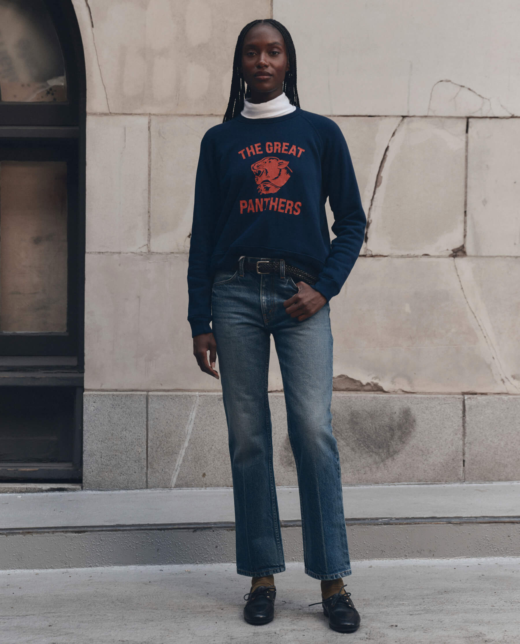 Model wearing navy fleece sweatshirt with red Growling Panther graphic and jeans