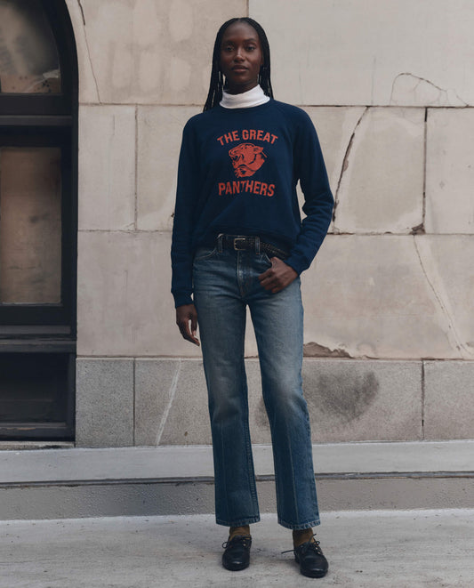 Model wearing navy fleece sweatshirt with red Growling Panther graphic and jeans