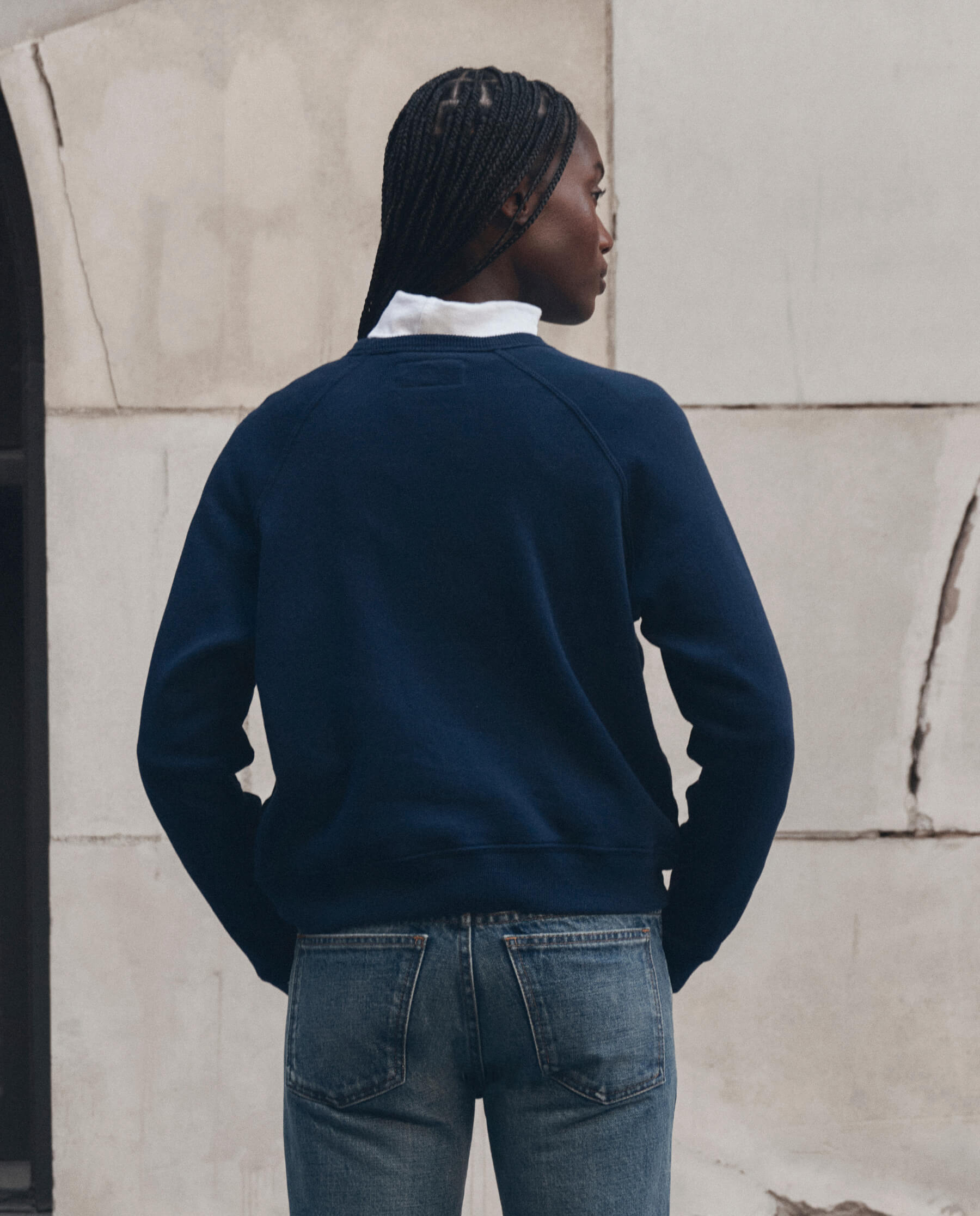 Model wearing navy blue fleece crew neck sweatshirt layered over white collar with jeans