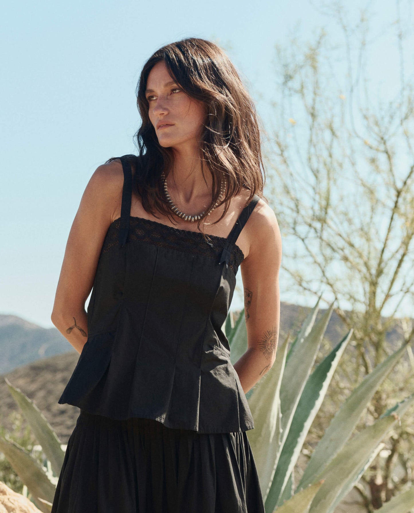 Model wearing black lace-trimmed Victorian tank top with wide straps in desert setting