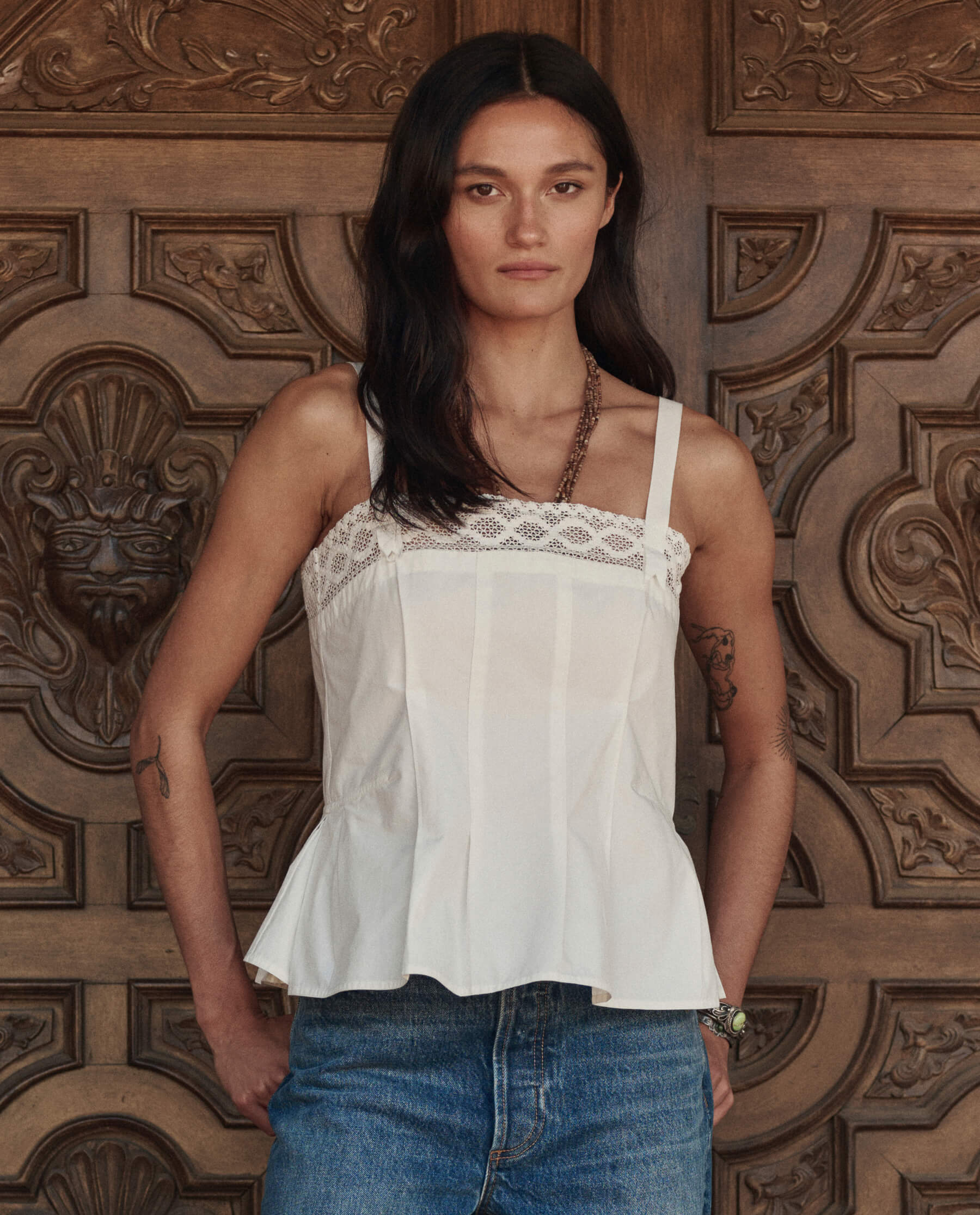 Model wearing white structured Victorian tank top with lace trim and peplum hem