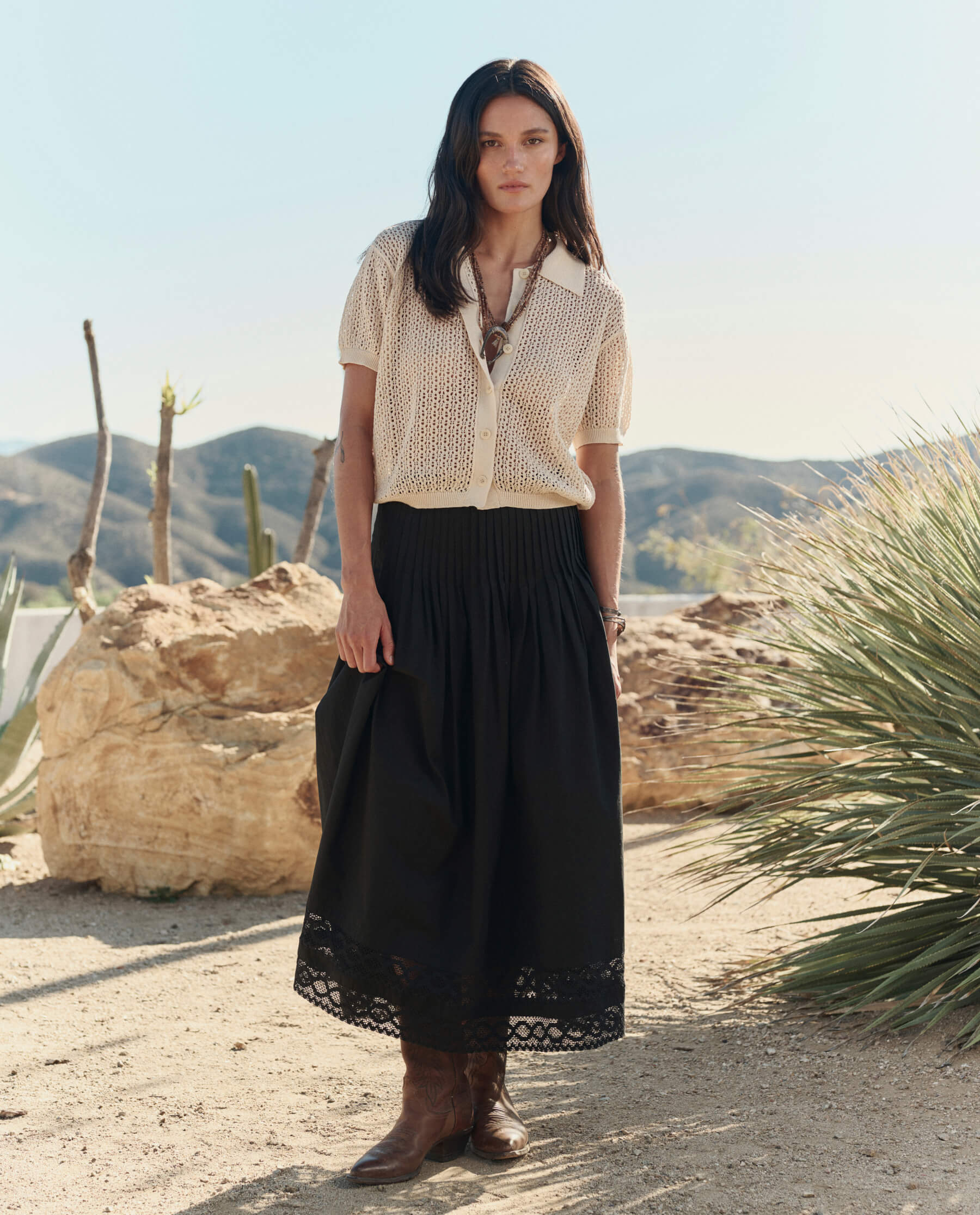 Model wearing black midi Victorian skirt with lace hem trim and brown cowboy boots in desert setting