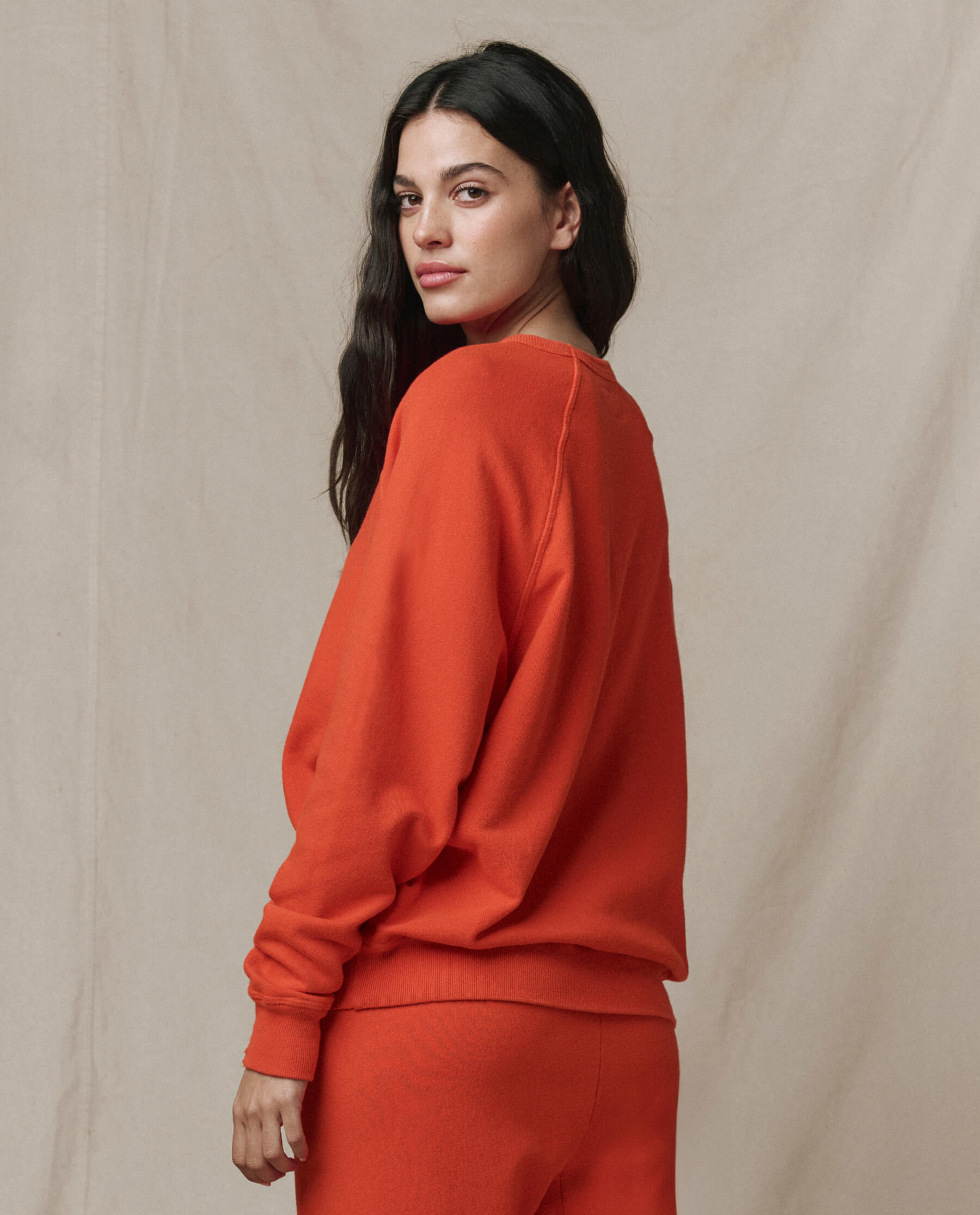 Woman wearing orange-red college sweatshirt in professional studio setting