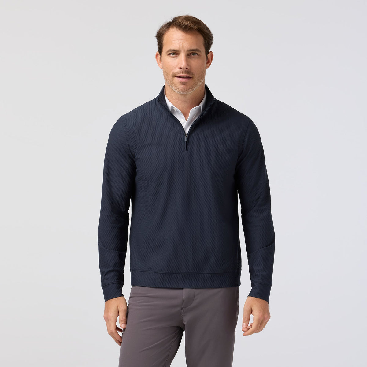 Man wearing navy quarter-zip pullover with subtle texture over white collar shirt