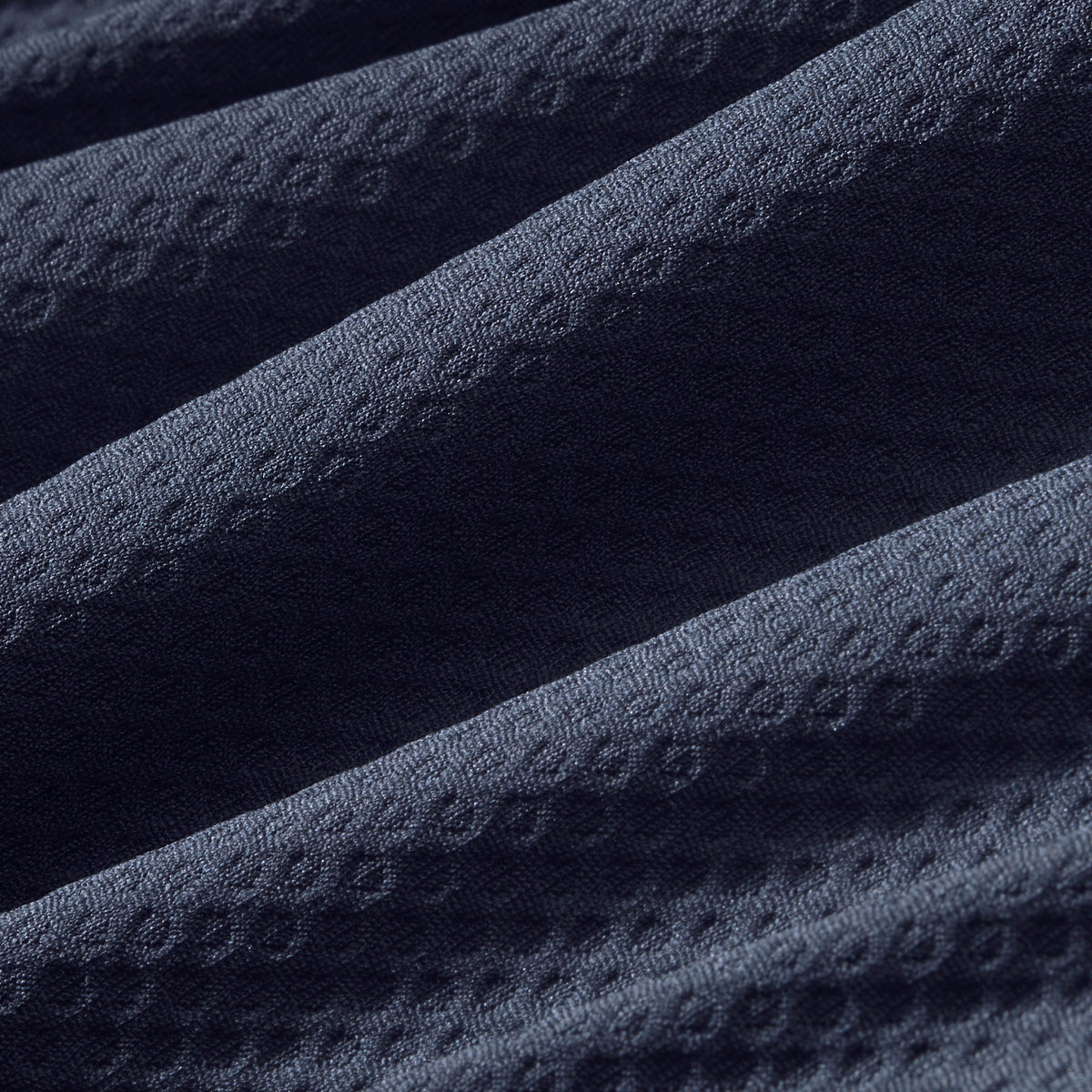 Close-up swatch of navy blue textured fabric with subtle geometric pattern for quarter zip