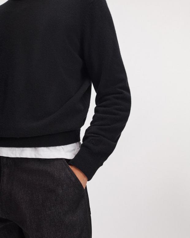 Back view of model wearing black cashmere crew neck sweater with dark denim