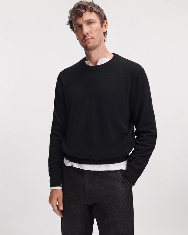 Male model wearing black cashmere crew neck sweater layered over white shirt