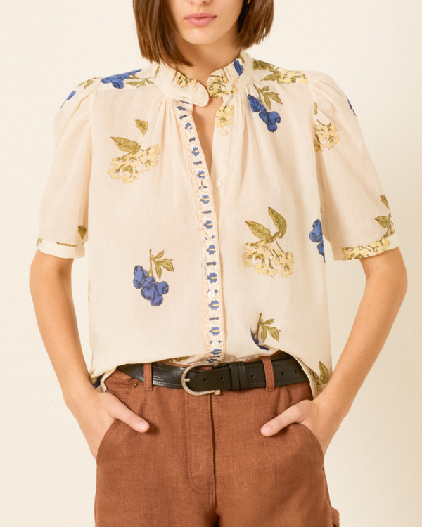 Woman wearing off-white blouse with blue floral print and puff sleeves