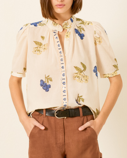 Woman wearing off-white blouse with blue floral print and puff sleeves