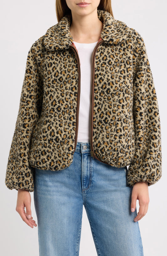 Woman wearing tan leopard print fleece zip-up jacket over white tee and jeans