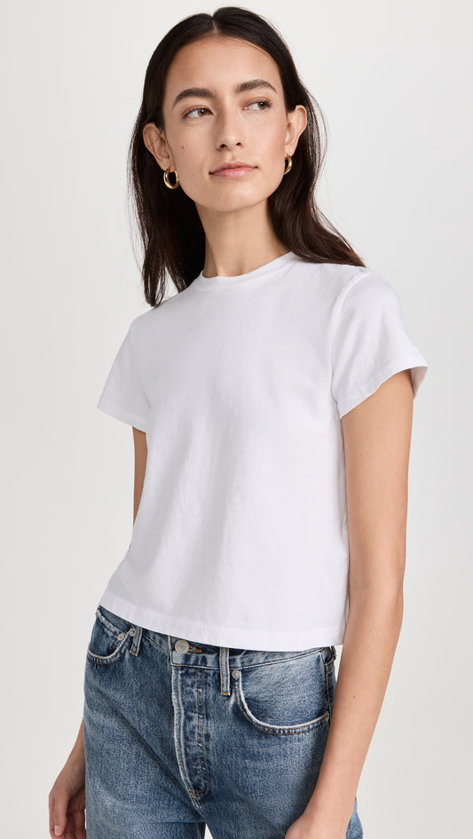 Woman wearing white short-sleeve crewneck t-shirt with blue jeans against neutral background
