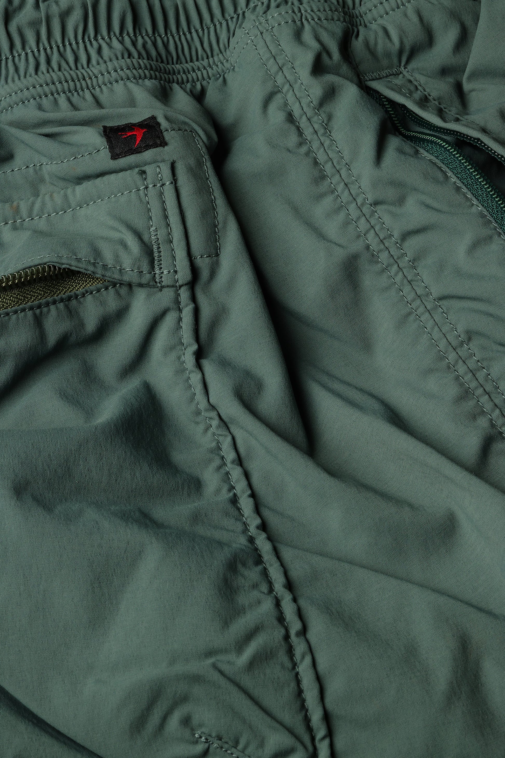 Relwen Airtex Hybrid shorts in olive green showing elastic waistband, zippered pockets, and detailed stitching construction.