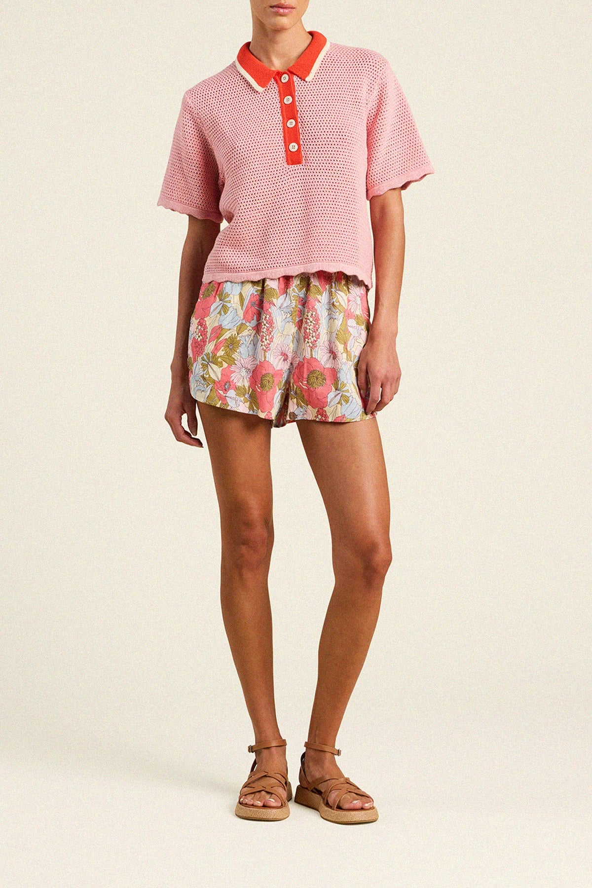 Trovata Amalia pink knit polo top with red collar and button placket, styled with floral shorts and platform sandals.