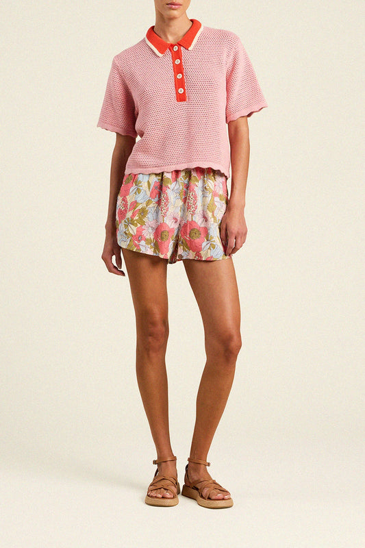 Trovata Amalia pink knit polo top with red collar and button placket, styled with floral shorts and platform sandals.