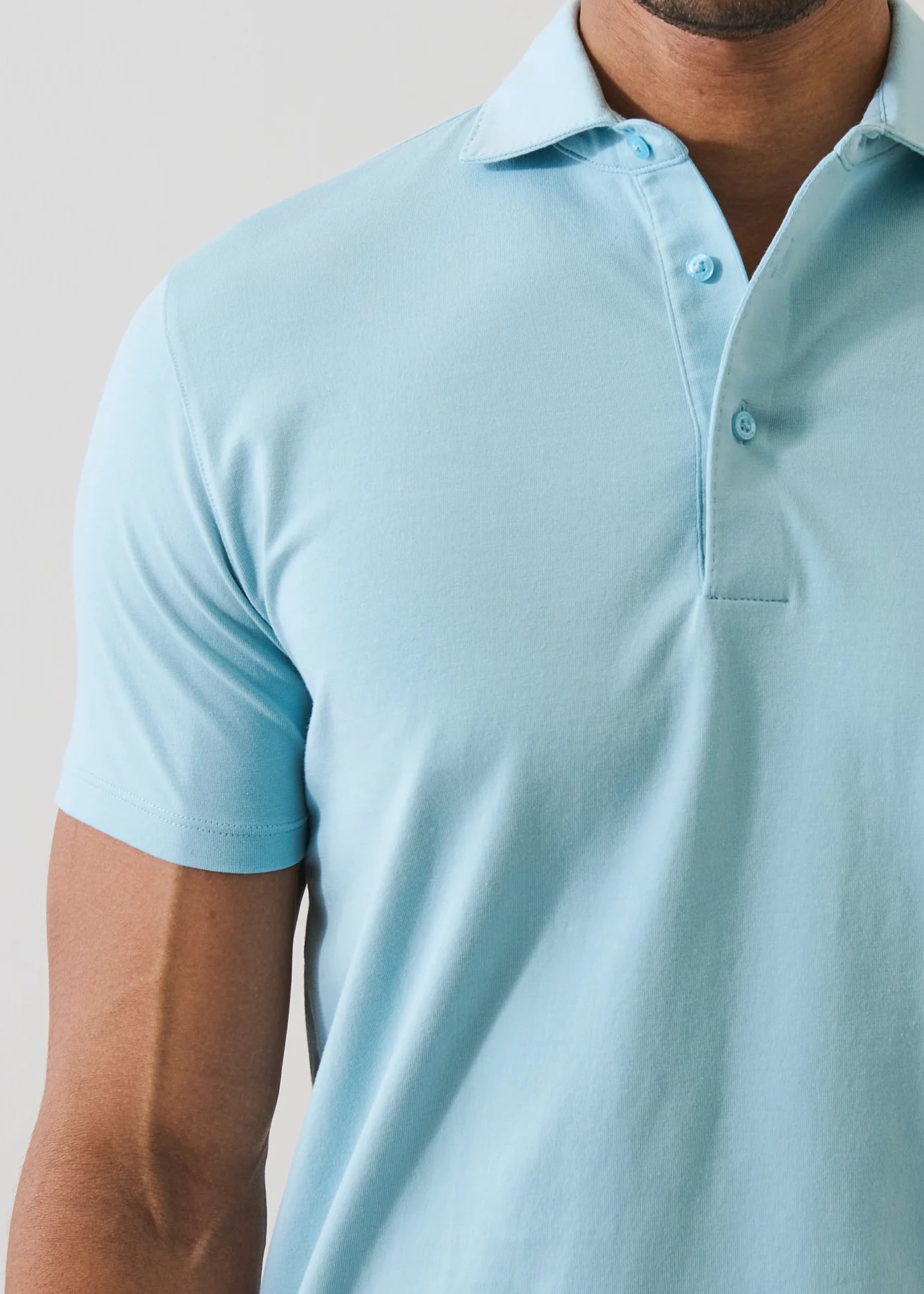 Man wearing a light blue Patrick Assaraf short-sleeve pima cotton polo shirt with collar and buttons.