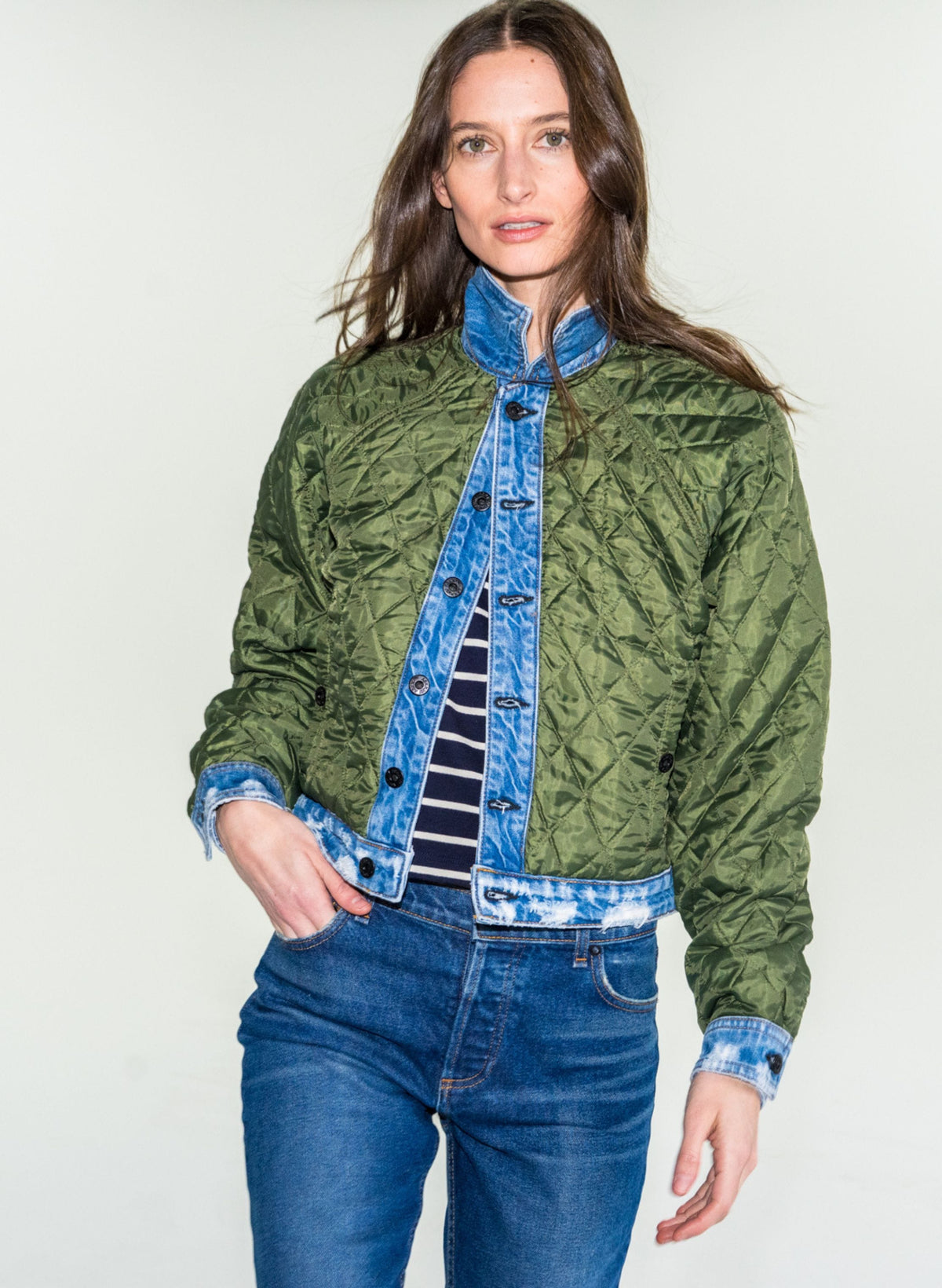Model wearing olive green quilted liner jacket over denim jacket with blue jeans