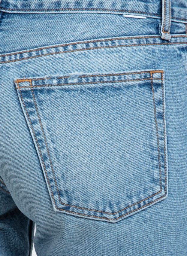 Close-up of light blue denim jeans back pocket with contrast orange stitching