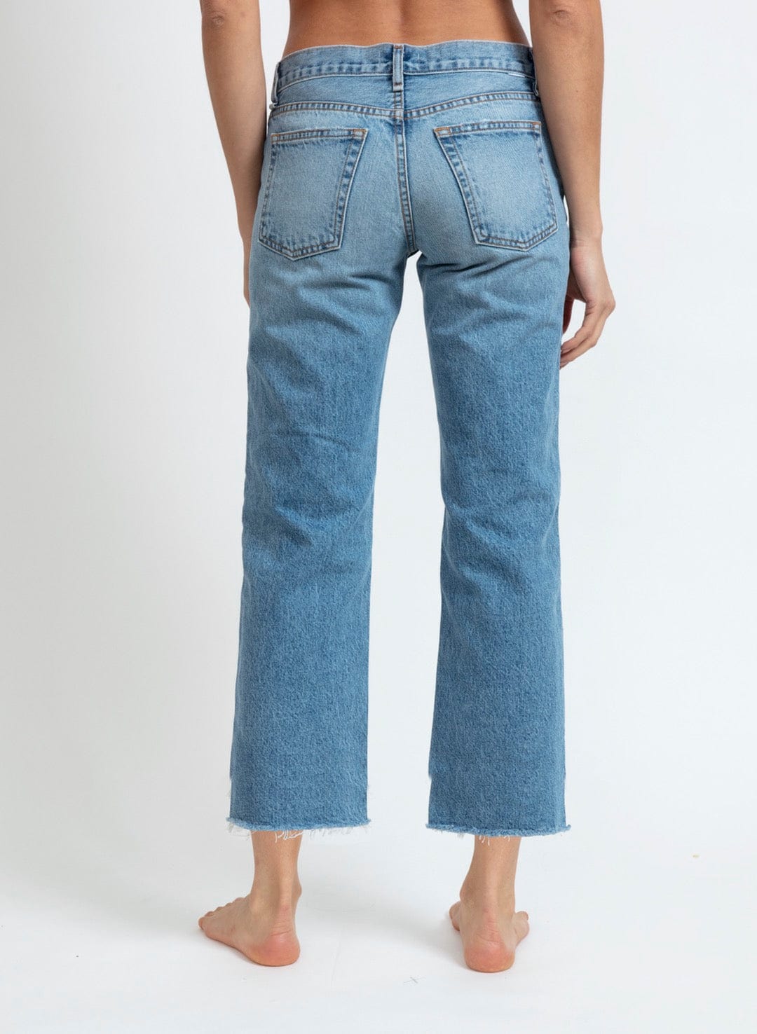 Back view of low rise straight leg cropped jeans with raw hem in medium blue wash