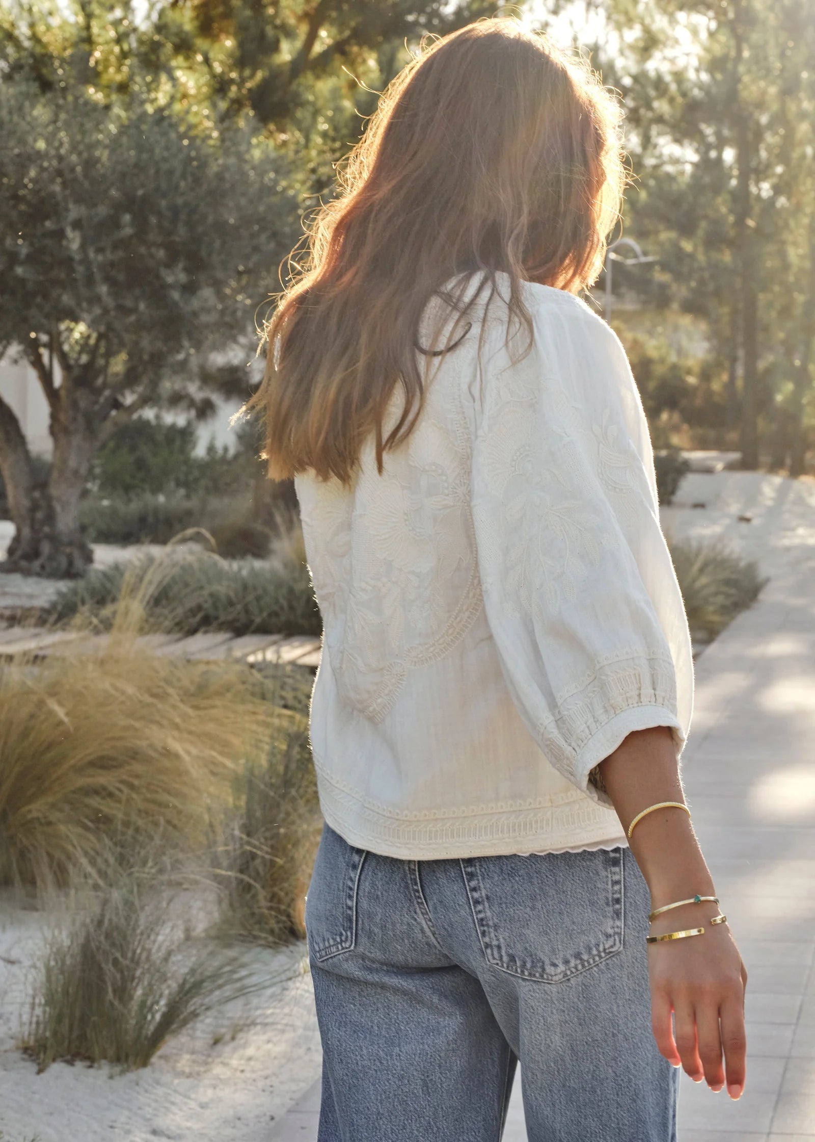 Woman wearing MABE Averi white embroidered jacket with long sleeves and decorative trim, paired with denim jeans.