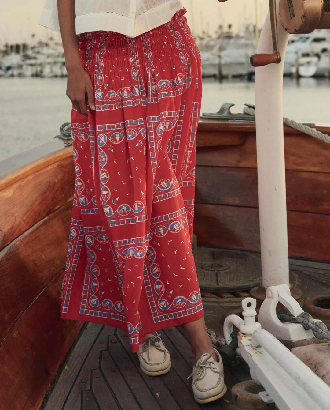 The Great red bandana print midi skirt with elastic waist worn on wooden boat deck with boat shoes