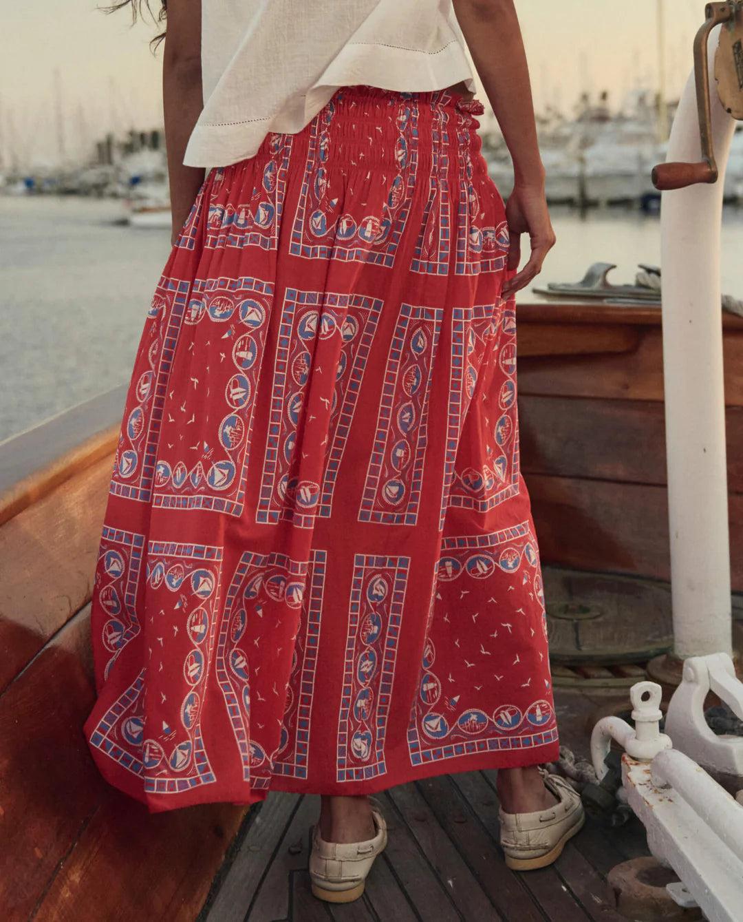 Woman wearing The Great Canary Skirt in red sailboat bandana print, a flowing midi-length skirt with geometric nautical pa...