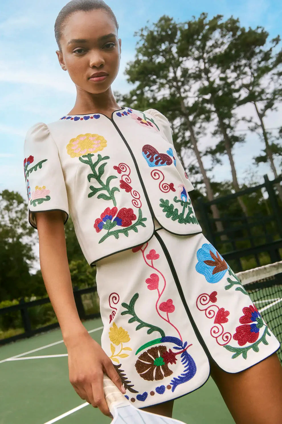 Hunter Bell Beeson embroidered floral crop top and matching mini skirt set with colorful folk-inspired motifs and black trim.