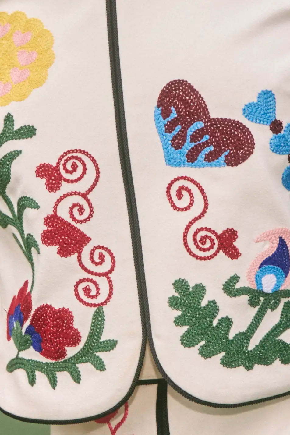 Embroidered white fabric panels featuring colorful floral motifs with decorative stitching and contrasting trim edges.