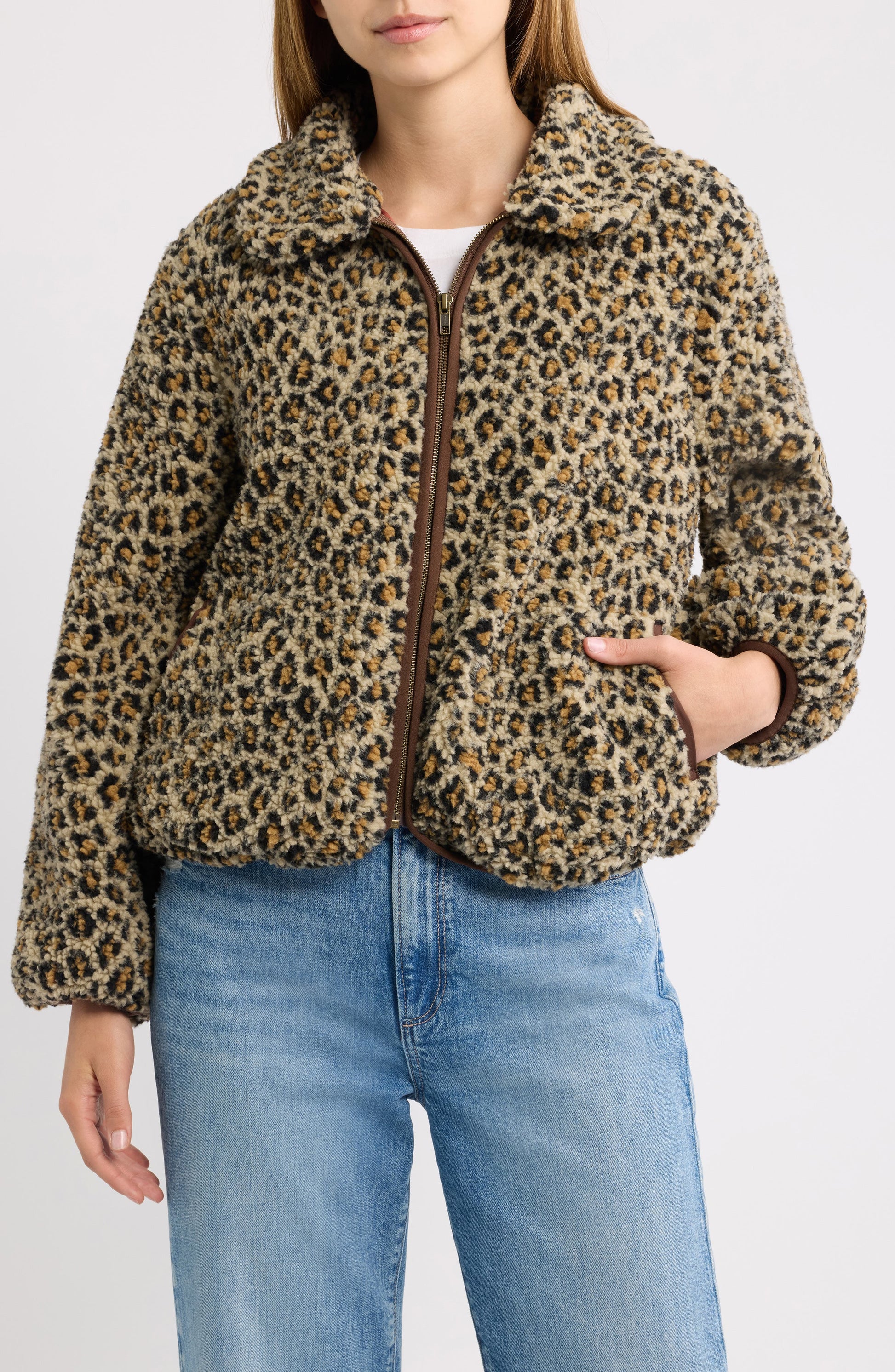 Model wearing tan leopard print fleece zip-up jacket with brown leather trim detailing