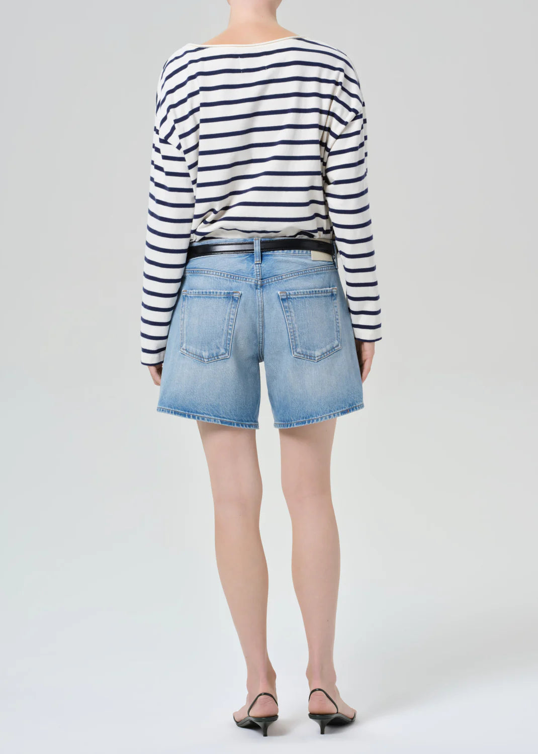 Back view of woman wearing Citizens of Humanity Billie Relaxed Short in light blue denim with striped long-sleeve top and ...