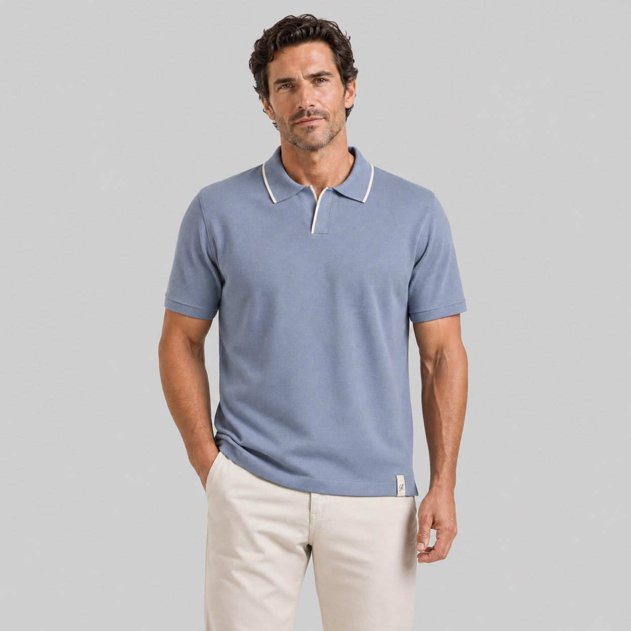 Man wearing dusty blue luxury linen polo shirt with white trim and beige pants