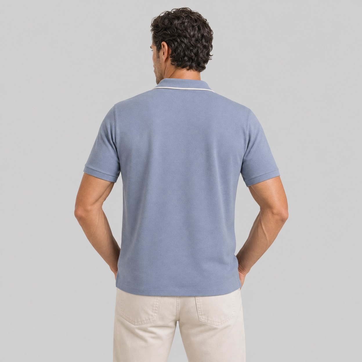 Man wearing dusty blue linen polo shirt viewed from behind with hands on hips