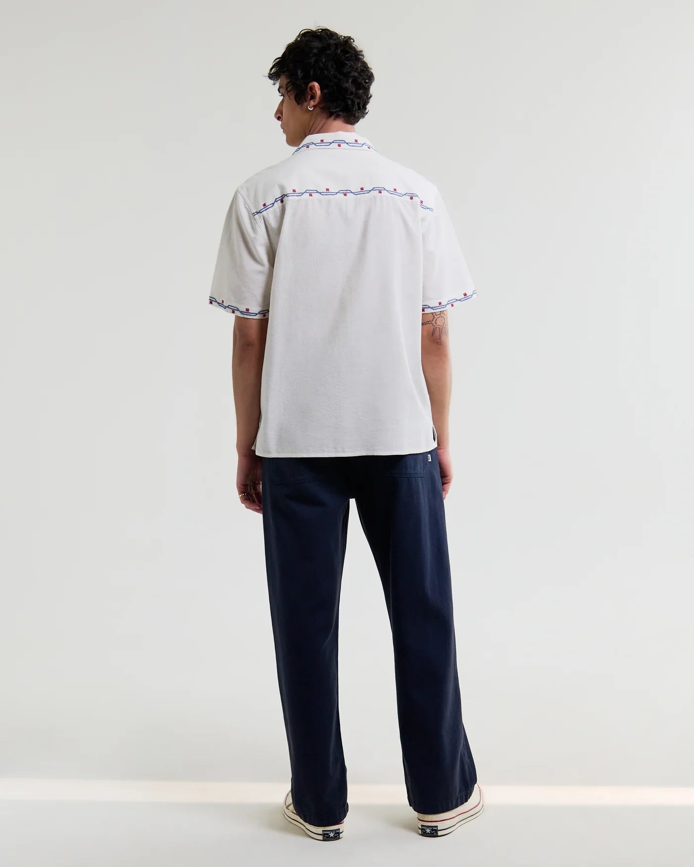 Back view of person wearing Wax London Didcot short-sleeve shirt with cross stitch border trim and navy trousers
