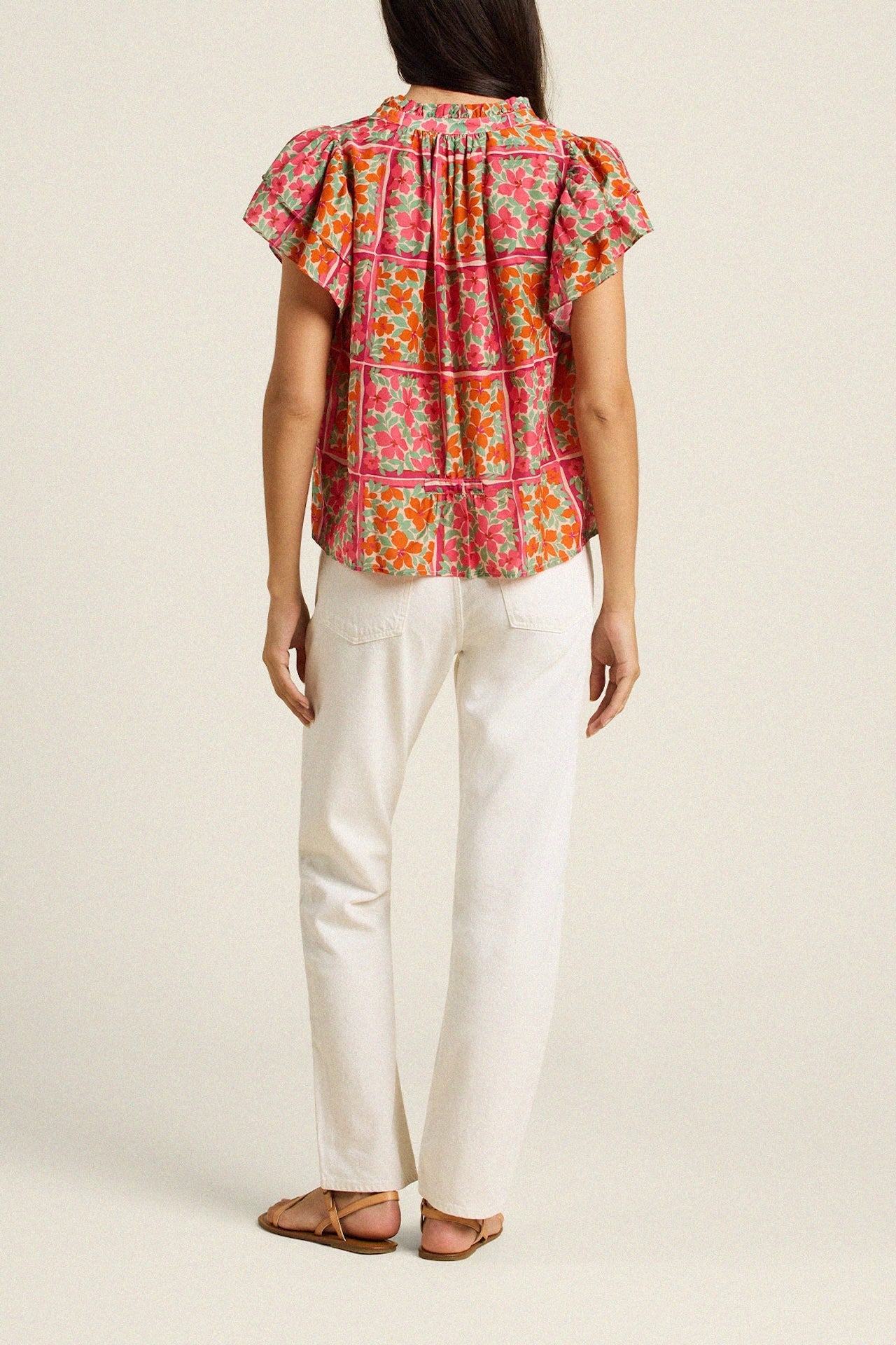Back view of woman wearing colorful floral blouse with white pants