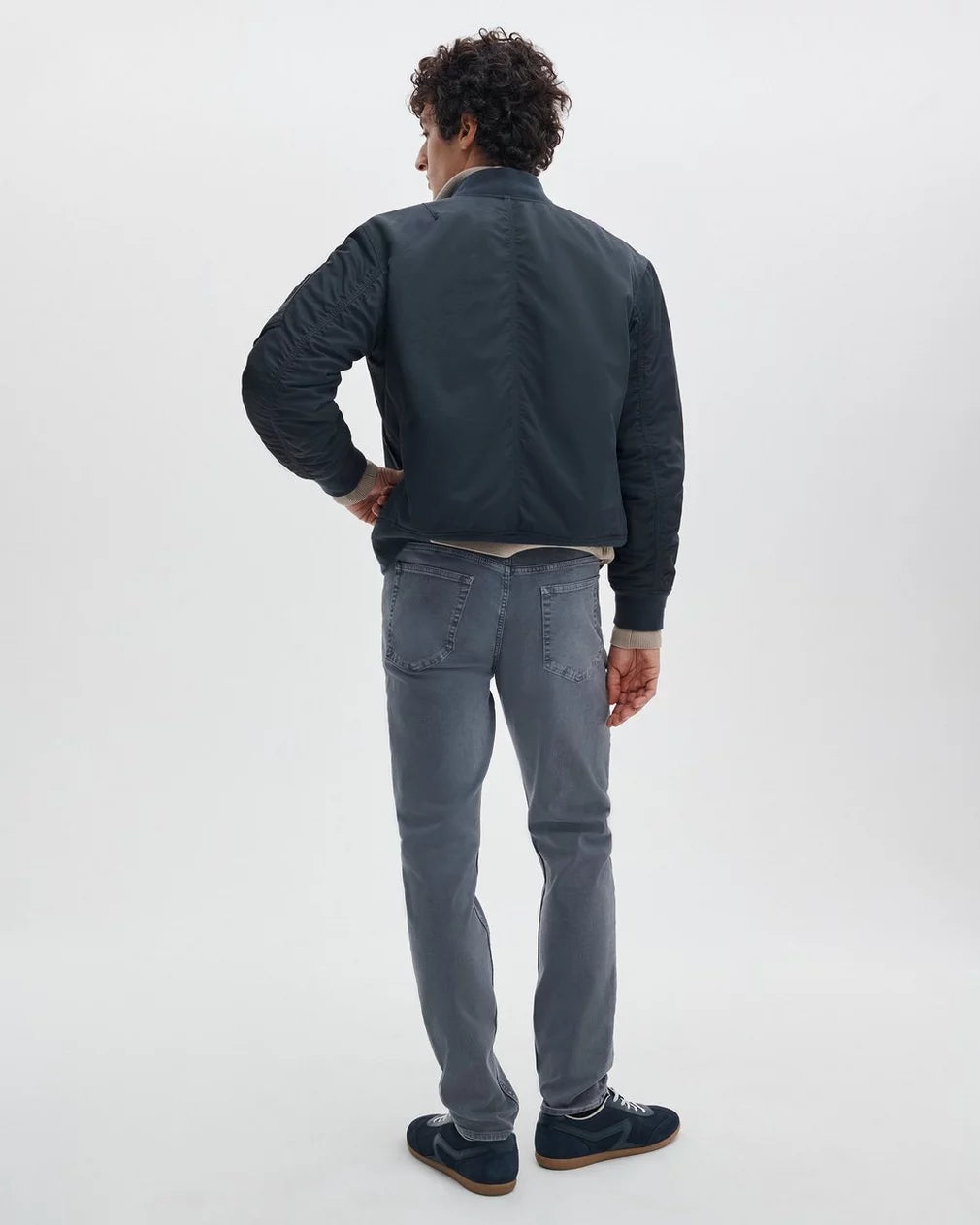 Man wearing Rag & Bone Fit 3 Airflex Bowery jeans in gray, shown from behind in full body view.