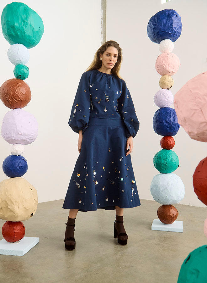Model wearing navy midi skirt with multicolor splatter print detailing and balloon sleeves
