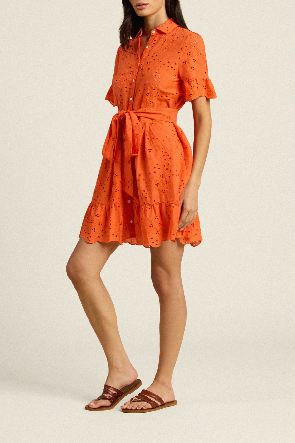 Woman wearing orange eyelet dress with button front, short sleeves, and ruffle hem