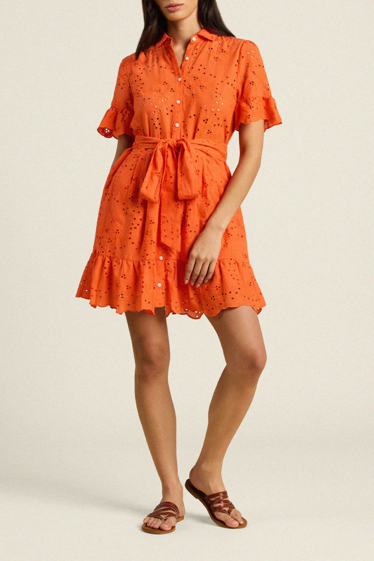 Woman wearing orange eyelet button-up dress with tie waist and ruffled hem