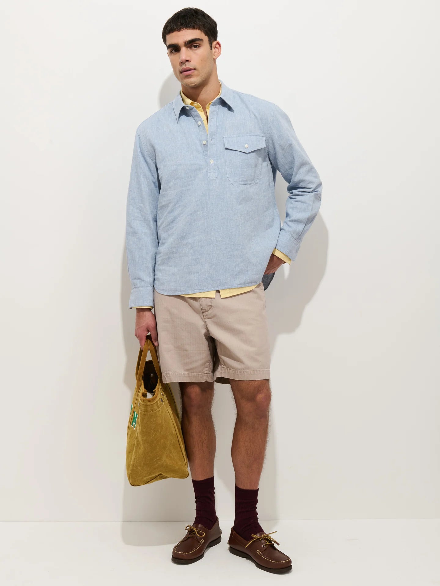 Alex Mill Carter long sleeve popover shirt in light blue cotton linen with chest pocket, styled with khaki shorts.