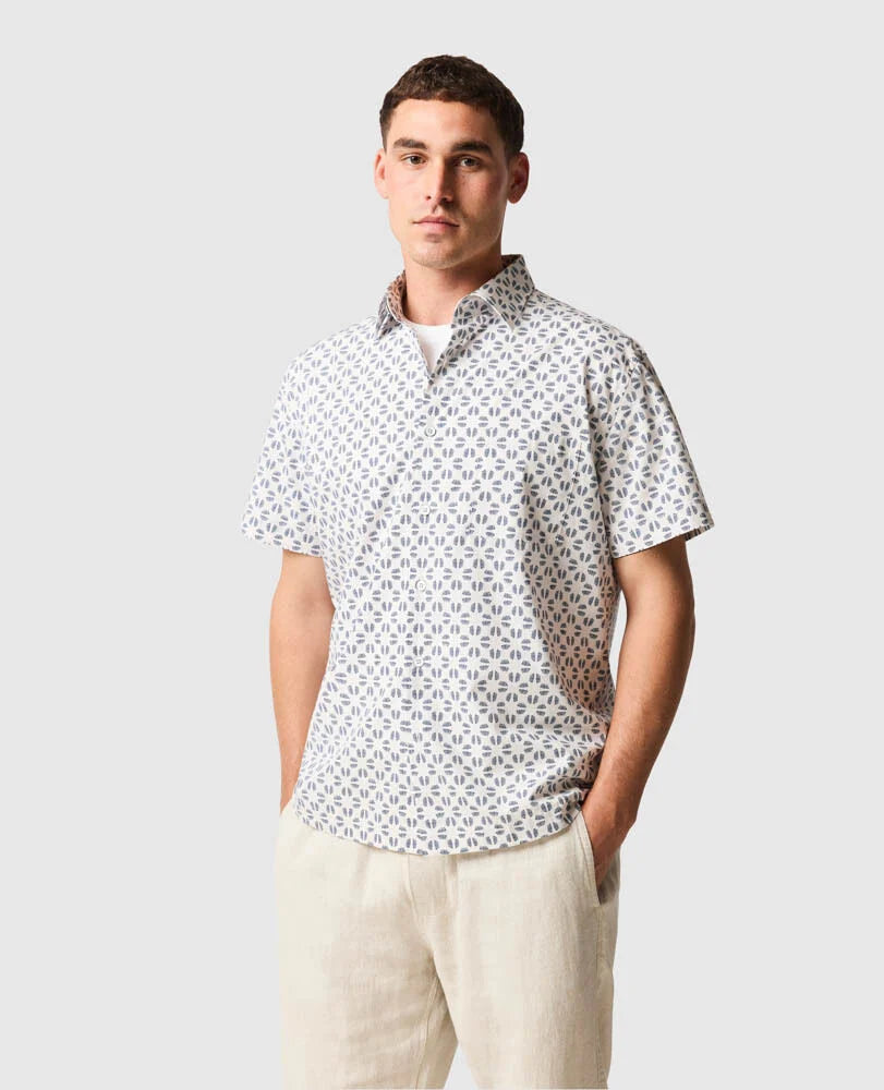 Man wearing Rodd & Gunn Crown Hill short-sleeve shirt with geometric pattern, paired with light-colored trousers.