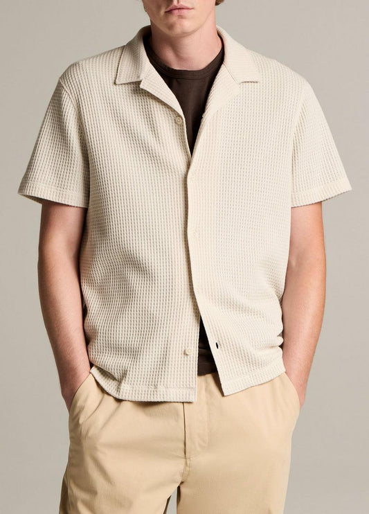 Man wearing cream waffle-textured short sleeve button-down shirt with beige pants