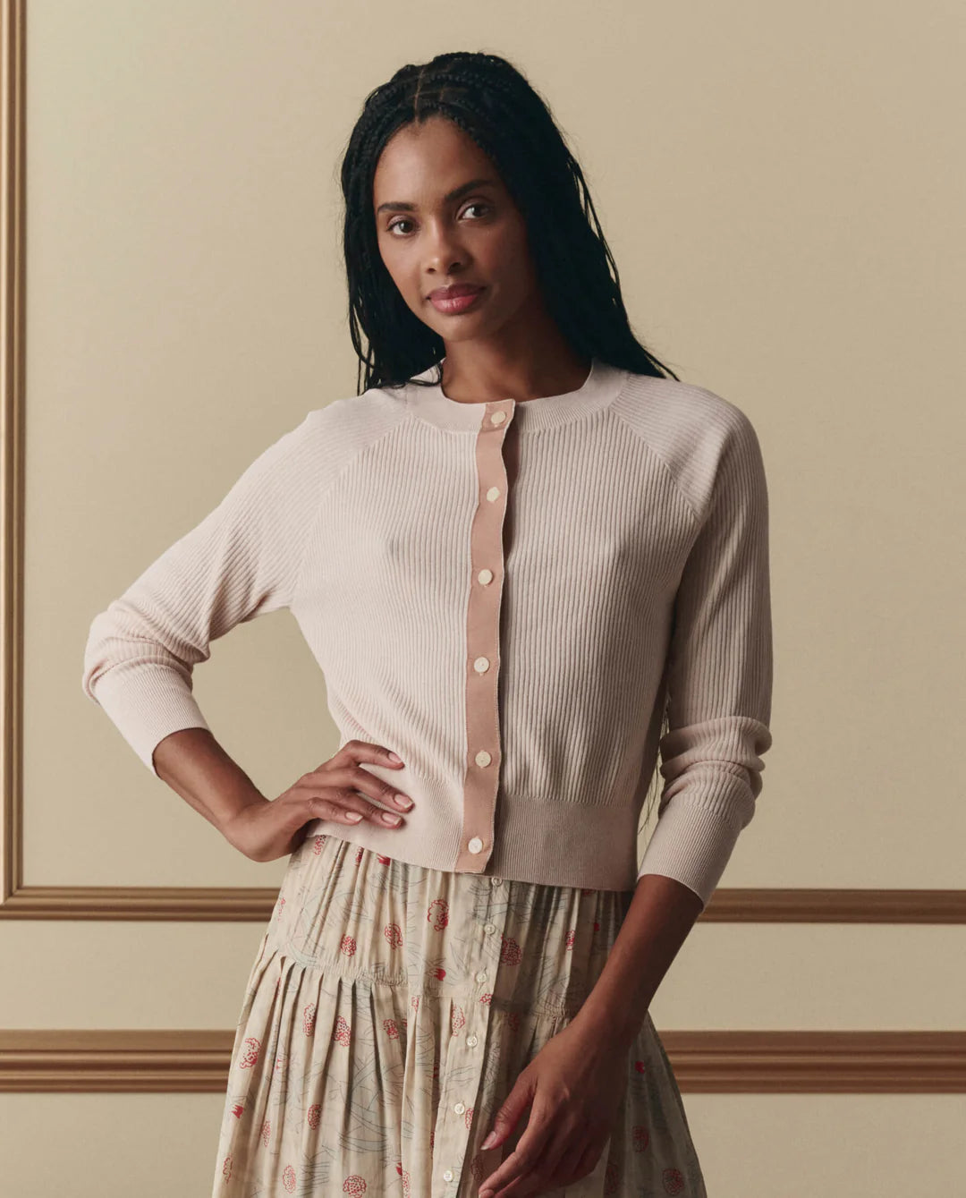 Woman wearing The Great soft ribbed button-front cardigan with long sleeves over a floral print dress.